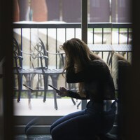 Une jeune femme se prend la tête dans la pénombre.
