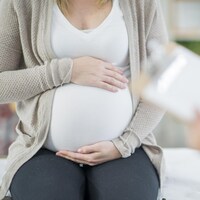 Une femme enceinte tient son ventre.