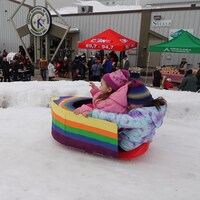 Deux enfants glissent dans une luge transformée en bateau multicolore.