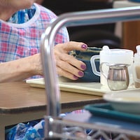 Gros plan sur la main d'une dame âgée qui tient un bol de nourriture.