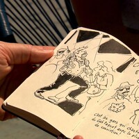 Le bédéiste tient son carnet à dessin avec des illustrations d'un chanteur et des spectateurs.