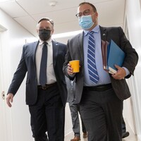 Jonathan Lapierre et François Legault marchent dans un corridor avec des masques au visage.