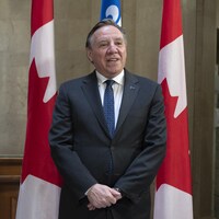 M. Legault prenant la pose aux côtés de la gouverneure générale Mary Simon devant des drapeaux du Canada et du Québec.