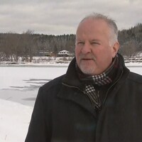 François Veilleux en manteau d'hiver, dehors devant une rivière.