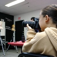Une jeune fille prend une photo dans un local à l'aide d'un appareil numérique.