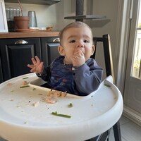 Le bébé est dans une chaise haute dans la cuisine familiale.