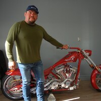 L'homme avec une rutilante moto rouge.