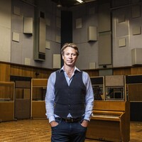 Un homme pose dans un studio d'enregistrement de musique.