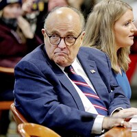 Rudy Giuliani, assis au côté d'une autre avocate du camp Trump, se retourne et inspecte la salle durant une audience visant à mettre en doute les résultats du vote au Michigan, le 7 décembre 2020. 