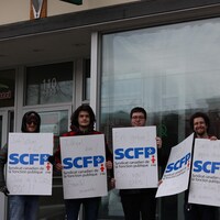 Des employés brandissant des pancartes syndicales devant une succursale de la SQDC.