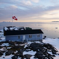 Un drapeau du Groenland flotte dans le vent au-dessus d'une maison.