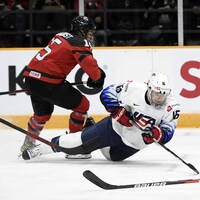 La hockeyeuse canadienne fait trébucher son adversaire américaine avec son patin.