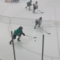 Deux jeunes hockeyeurs se disputent la rondelle sur la glace lors d'un tournoi.