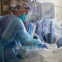 Une infirmière se penche sur un patient de la COVID-19 à l'hôpital.