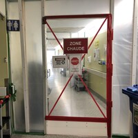 Une porte où l'on peut lire « ZONE CHAUDE » à l'entrée d'une zone COVID-19.