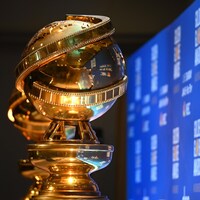 Deux trophées Golden Globes vus de près, devant un écran bleu. 