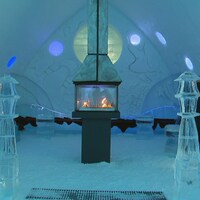 Un intérieur entièrement sculpté dans de la glace. Au milieu de la pièce, on aperçoit un poêle à l'intérieur duquel crépitent des flammes.