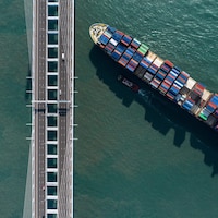 Cette photo aérienne montre un porte-conteneurs naviguant sous un pont à Hong Kong.