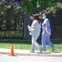 Deux infirmières marchent sur le trottoir.                  