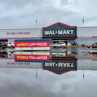 Le logo de Walmart se reflète dans l'eau recouvrant la chaussée. 
