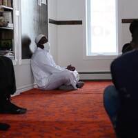 Des personnes sont assises par terre dans une mosquée.