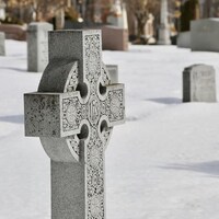 Une croix celtique orne une des tombes du cimetière Saint-Patrick, par une journée d'hiver. On peut apercevoir d'autres tombes derrière. L'endroit respire la paix et le calme. 