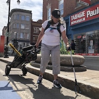 Nathalie Bernier, participante au projet Contribuer à un centre-ville accueillant, ramasse un déchet au centre-ville de Trois-Rivières à l'aide d'une pince. 