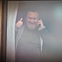Un homme sourit à travers une fenêtre.