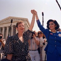 Deux femmes brandissent en l'air leurs deux mains jointes.