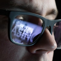 Reflet d'une image de casino virtuel dans les lunettes d'un homme.