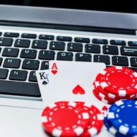 Des jetons de poker et des cartes sont posés sur un clavier d'ordinateur. 
