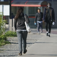 Des jeunes adultes marchent sur un trottoir.