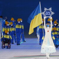 La délégation suit une femme qui tient une affiche en forme de flocon avec le nom de l'Ukraine. 