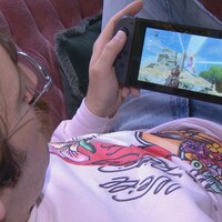 Une personne joue à un jeu vidéo qu'il tient entre ses mains.