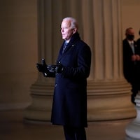 Joe Biden devant les caméras et le drapeau américain 