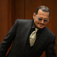 Johnny Depp en veston-cravate avec des lunettes fumées.