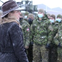Mélanie Joly se tient devant des soldats en hiver. 
