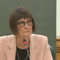 Judy Ferguson regarde sur le côté et écoute attentivement.