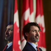 Justin Trudeau souriant devant un drapeau du Canada.