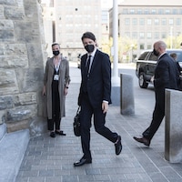 Justin Trudeau marche en direction du parlement en regardant le photographe.