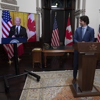 Justin Trudeau regarde Joe Biden, sur un écran, en souriant.