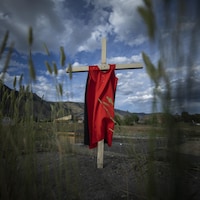 Une robe rouge suspendue sur une croix à la suite de la découverte des sépultures non marquées près de l'ancien pensionnat pour Autochtones de Kamloops, en Colombie-Britannique, en mai 2021.