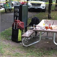 Divers objets jonchent une table de pique-nique dans un parc.