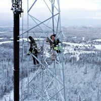 Des travailleurs dans la tour de communications, dans le paysage enneigé de Lac-Édouard.