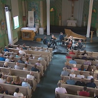 Des gens dans une église écoutent des musiciens.