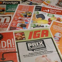Des circulaires de plusieurs épiceries étalées sur une table.