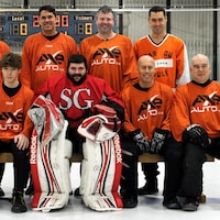 Une équipe complète de hockey bottine avec un gilet orange.