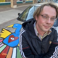 Byrun Beet et sa voiture personnalisée ornée de peintures d'oiseau colorées.