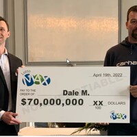 Dale McEwen reçoit son chèque de 70 millions d’un représentant de Sask Lotteries. 
