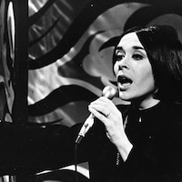 La chanteuse Louise Forestier chante sur scène avec un micro à la main.
